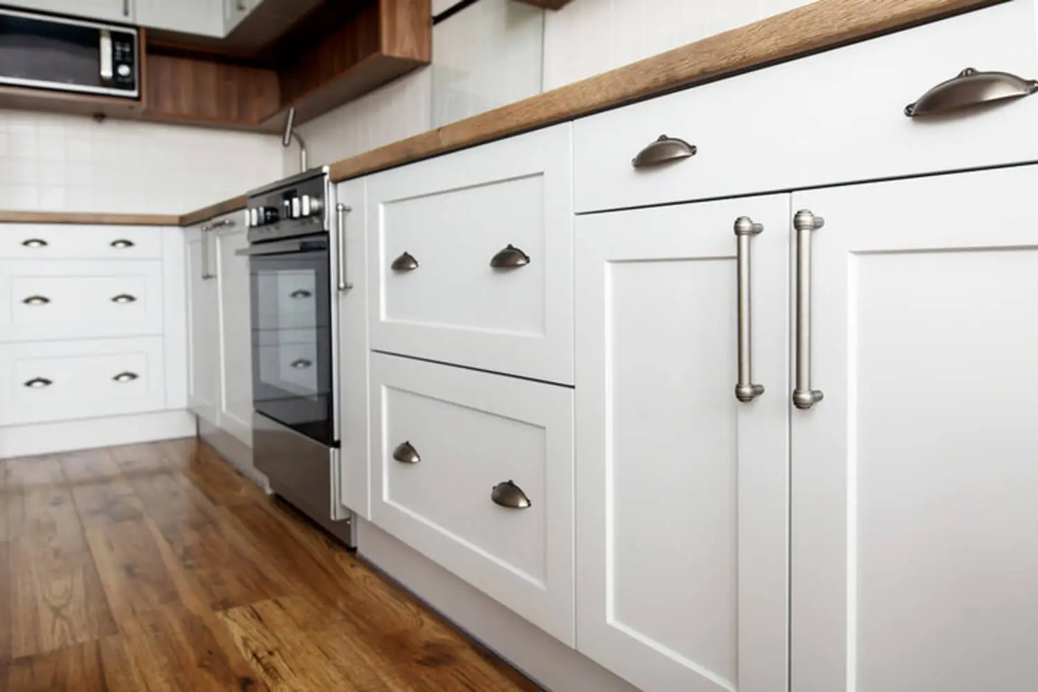 Clean white painted kitchen cabinets with brushed nickel hardware, showing a well-maintained finish that has held up to daily use.