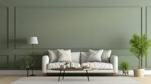 Sage green accent wall with panel moulding behind a white sofa, showing how a single wall can add depth and personality to a living room.