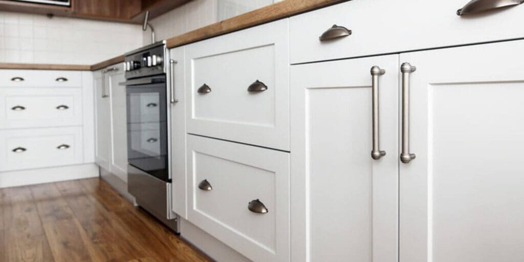 Clean white painted kitchen cabinets with brushed nickel hardware, showing a well-maintained finish that has held up to daily use.