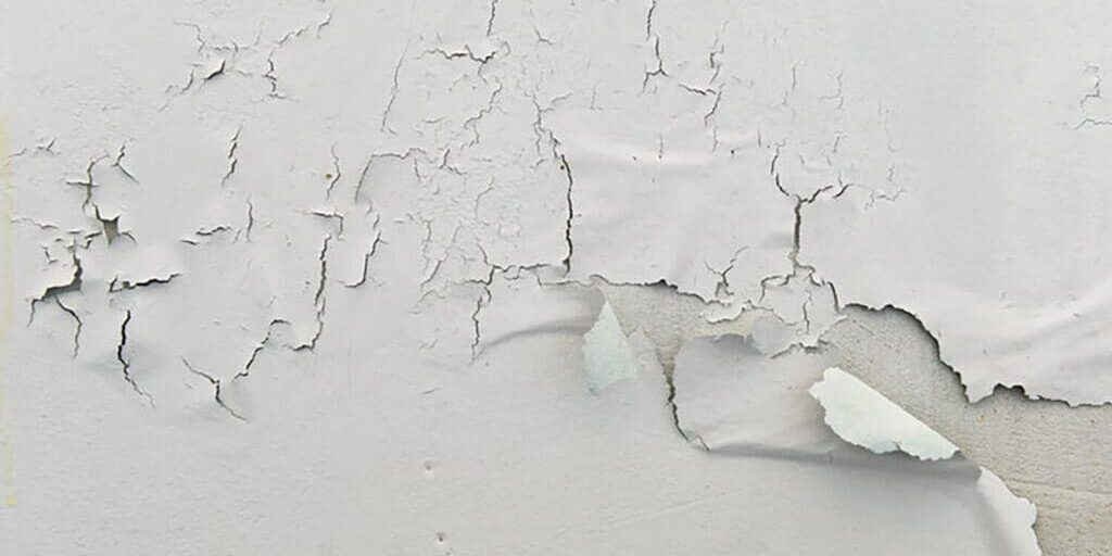 Peeling paint on an interior wall showing when peeling paint signals a bigger interior issue due to underlying wall damage