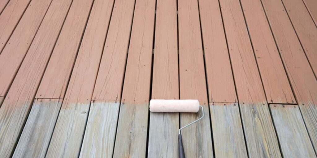 A deck being repainted, showing weathered bare wood on one side and freshly applied paint on the other, illustrating signs a deck needs to be repainted.